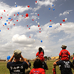 People watching balloons floating in the air.