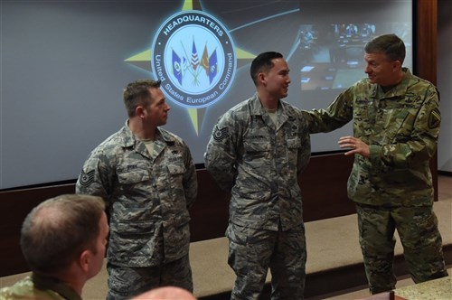 U.S. European Command Deputy Commander Lt. Gen. W. Burke Garrett III presents a coin to Tech. Sgt. Joseph Hanson, analyst, and Tech. Sgt. Mitchell Pope, information manager for outstanding duty performance on Aug. 31, 2016. 