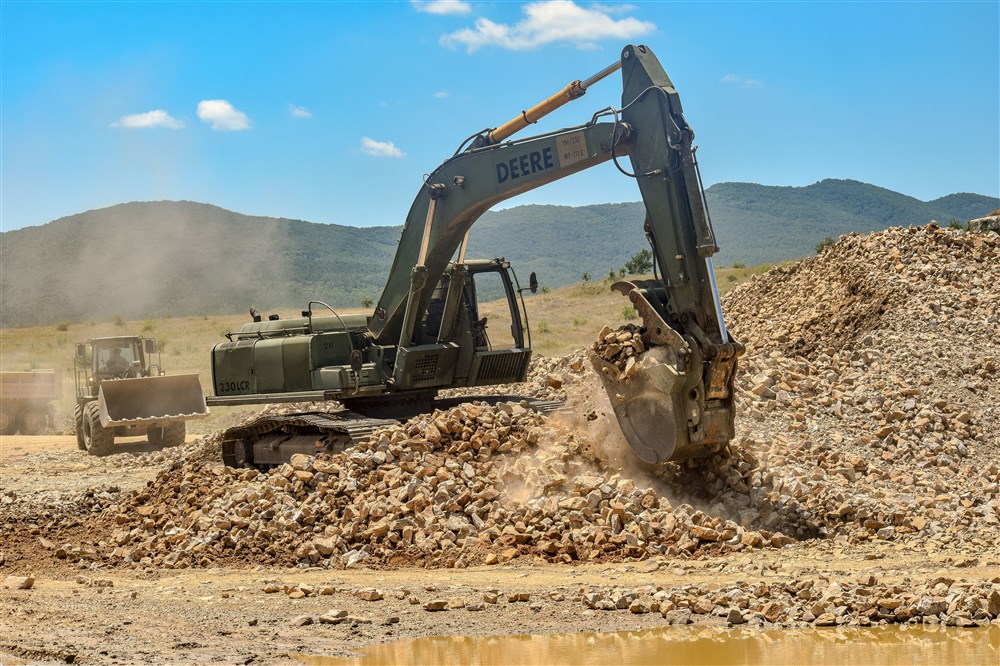 A hydraulic excavator operated by military engineers from the 841st Engineer Battalion, U.S. Army Reserve moves rock near a road under construction on July 6, 2016 at Novo Selo Training Area, Bulgaria during Operation Resolute Castle 2016.  Soldiers from the 841st Engineer Battalion spent the summer of 2016 working with service members from the Tennessee Army National Guard and Mississippi Army National Guard to improve a tank training range and ammunition holding area in Bulgaria.  (U.S. Army photo by Capt. Kimberlee Lewis, 841st Engineer Battalion, U.S. Army Reserve)