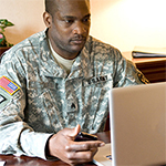 Service member sitting at a desk looking at a laptop 