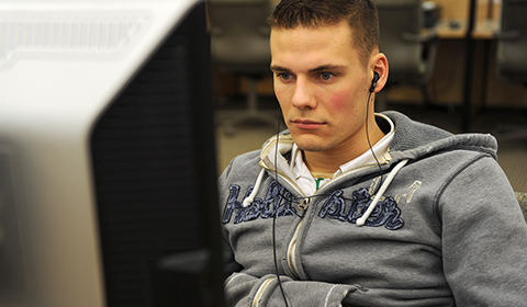 Service member with headphones sitting in front of a computer