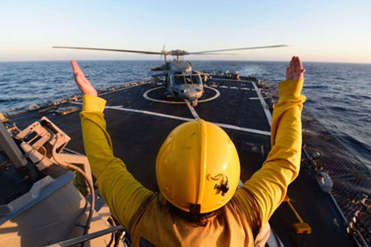 160714-N-FP878-218 A Boatswain’s Mate signals a MH-60S Seahawk from Helicopter Sea Combat Squadron 22, during flight deck qualifications aboard guided-missile destroyer USS Ross (DDG 71).