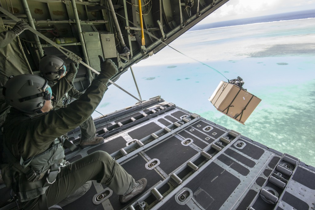 36th Airlift Squadron loadmaster and Col. TY Chamberlain, 36th Wing vice-commander, drops a low-cost, low-altitude bundle to Kayangel Atoll, Republic of Palau, Dec. 11, 2015, during Operation Christmas Drop. This year marks the 64th year of Operation Christmas Drop, which began in 1952, and is the first trilateral execution of the event with support from Japan Air Self-Defense Force and Royal Australian Air Force C-130s. (U.S. Air Force photo by Osakabe Yasuo/Released)