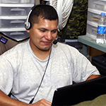 Service member wearing a headset at computer