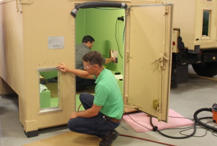 C4ISR Prototype Integration Facility (or PIF) engineers Dan Fitzpatrick, forward, and Garth Grove, rear, reconfigure the Intelligence Processing Center, or IPC-2, access panels to comply with the shelter’s fresh air and weight limitation requirements. U.S. Army CERDEC Photo/Kathryn Bailey, CERDEC CP&ID 