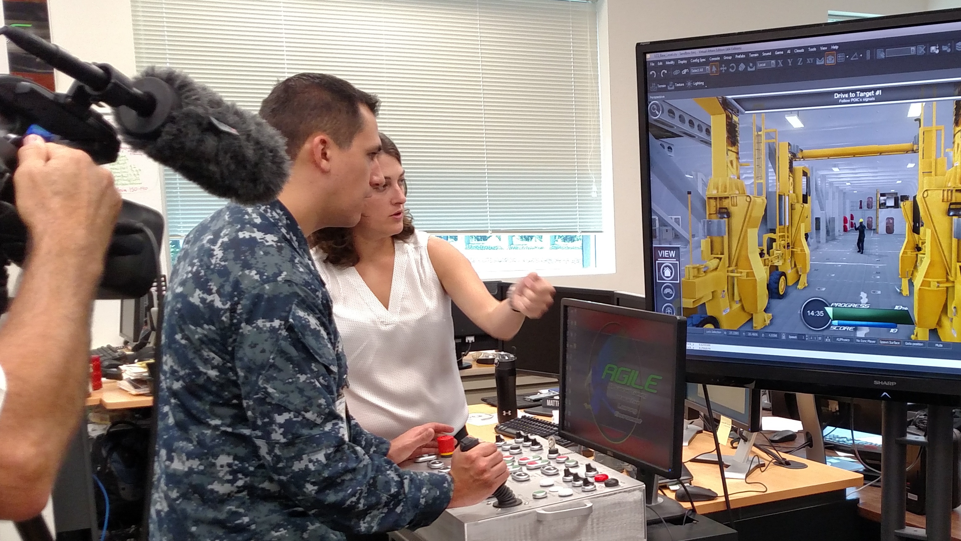 150715-N-WC128-001 ORLANDO, Fla. (July 15, 2015) Courtney McNamara, a computer scientist at the Naval Air Warfare Center Training Systems Division, demonstrates a Littoral Combat Ship (LCS) virtual cargo handling trainer to MC1(SW/AW) Elliot Fabrizio.   Fabrizio was in Orlando producing a "Weekly Wire Rundown" video feature about training in virtual reality environments.   (U.S. Navy Photo by Brian Roscoe/Released)