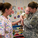 Female service member holding a baby.