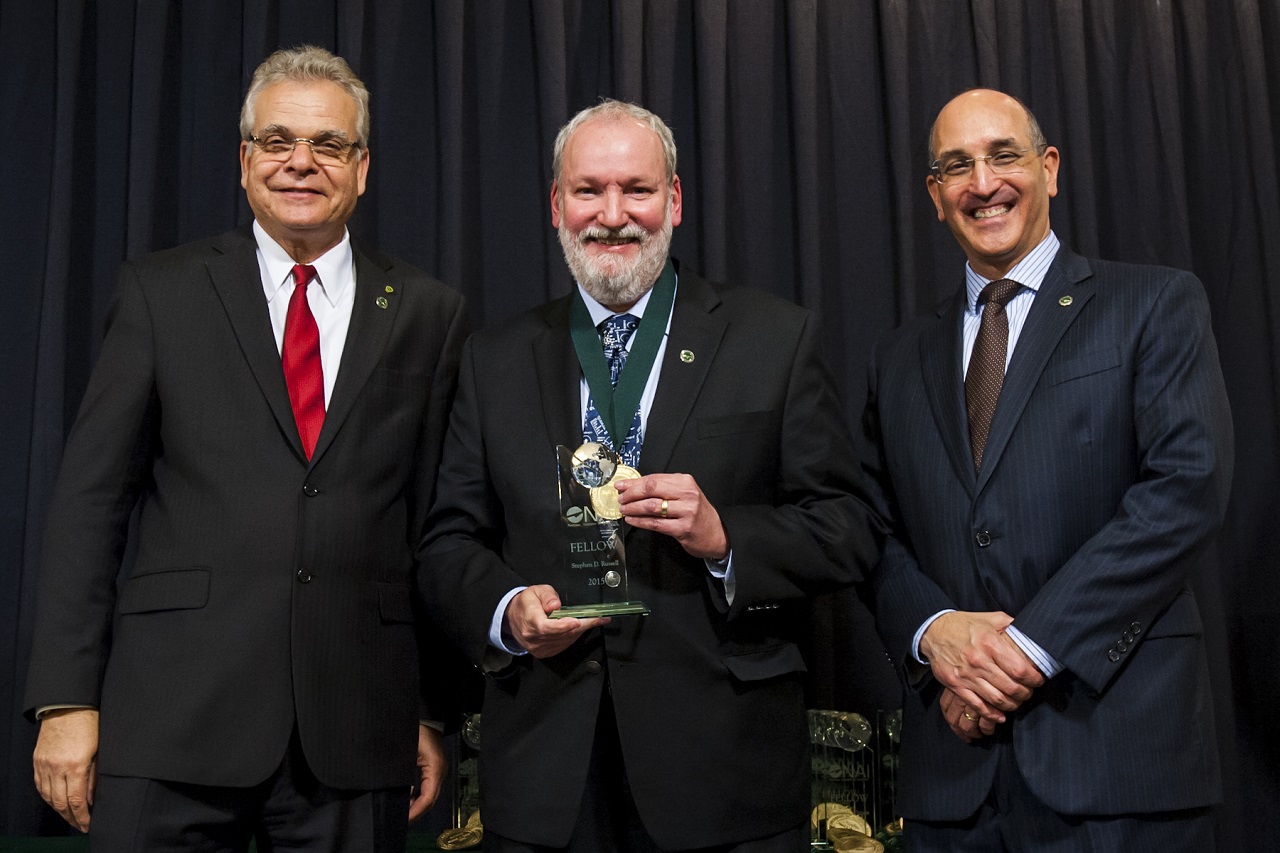 Dr. Stephen Russell, center, accepts induction into the National Academy of Inventors, April 15, 2016. Russell was welcomed into the organization by Paul R. Sanberg, president of the NAI and charter fellow, and Andrew H. Hirshfeld, U.S. commissioner for patents.

