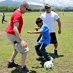 Men playing soccer with child