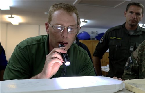 Staff Sgt. Christopher Officer, a criminal investigation special agent, shines a light on a foot impression inside a casting mold, during a Crime Scene Investigation course at Camp Bondsteel, Kosovo, July 13, 2016. (U.S. Army photo by: Staff Sgt. Thomas Duval, Multinational Battle Group-East public affairs)