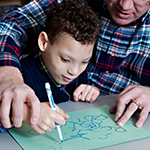 Man helping boy to draw a picture