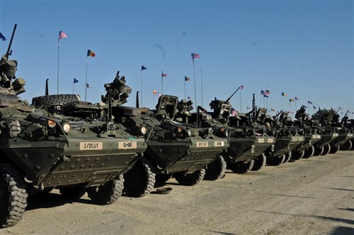 Troopers assigned to 2nd Squadron, 2nd Cavalry Regiment, place American, Romanian and NATO flags on their Stryker Combat Vehicles in preparation for the unit's Cavalry March to the Cincu Training Center, at Mihail Kogalniceanu Air Base, Romania, May 13, 2015. This event will not only focus on transporting troopers and their equipment to a new Romanian training facility, but it will also give the unit a chance to interact with the local populace while improving on relations with their host nation in support of Operation Atlantic Resolve-South. (U.S. Army photo by Sgt. William A. Tanner/released)