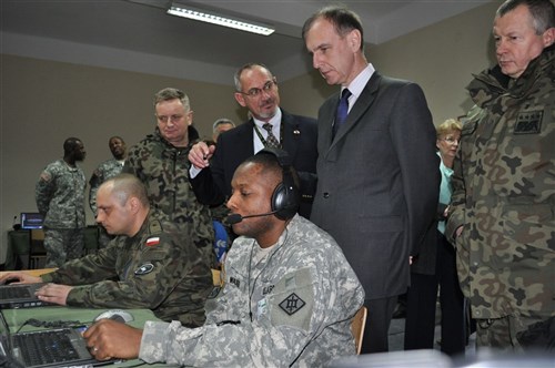 KIELCE, Poland &mdash; Thomas Lasch, the simulations director from the Joint Multi-National Simulations Center Grafenwoehr, explains the Unmanned Aerial Simulator operated by Army Sgt. 1st Class John J. Walker, the intelligence noncommissioned officer of the 18th Engineer Brigade, to Polish armed forces leaders Mar. 5 during Bagram VII at Bukowka Barracks here. (U.S. Army photo)