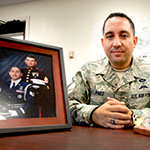 Service member sitting next to picture.