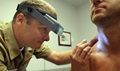 Navy Lt. Cmdr. Stephen Mannino examines a Sailor using a dermatascope and magnifying loops during a skin cancer screening at Naval Amphibious Base, Coronado, California.