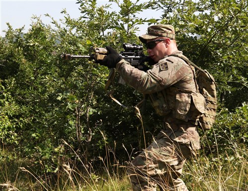 Spc. Timothy Squires, an infantryman assigned to the 1st Battalion, 41st Infantry Regiment, 2nd Infantry Brigade Combat Team, scans his sector of fire for any movement during a squad-level situational training exercise held in Dumnice, Kosovo, July 25, 2016. The purpose of the exercise was to train individual squad movements in preparation for a larger scale operation deemed Iron Eagle, later this year. (U.S. Army photo by: Staff Sgt. Thomas Duval, Multinational Battle Group-East Public Affairs)