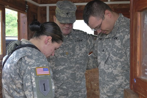 CAMP NOTHING HILL, Kosovo &mdash; Army Chaplain (Maj.) Maury D. Millican, of Bismarck, N.D. leads a prayer with Army Sgt. Ashley N. Timian, of Fargo, N.D., and Army Sgt. Chris J. Coombs, of Moorhead, Minn., during their guard duty shift at Camp Nothing Hill May 17.