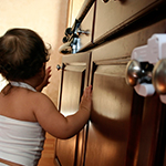 Young child trying to open a kitchen cabinet.