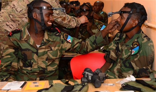 Djiboutian Army Cpl. Yosin, left, helps a fellow soldier, Mohamed, adjust his night vision goggle headmount during a night-vision goggle training course in Djibouti City, Djibouti, Oct. 10, 2016. Soldiers were tested on how quickly they could don their NVG gear during the class. (U.S. Air Force photo by Staff Sgt. Benjamin Raughton/Released)