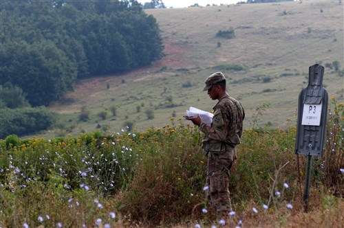 Pfc. Jordan White, an infantryman assigned to Headquarters and Headquarters Company, 1st Battalion, 41st Infantry Regiment, 2nd Infantry Brigade Combat Team, establishes terrain association during the land navigation portion of the Multinational Battle Group-East's Best Warrior Competition held on Camp Bondsteel, Kosovo, July 10. (U.S. Army photo by: Staff Sgt. Thomas Duval, Multinational Battle Group-East Public Affairs)