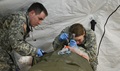 Army National Guard Sgt. Bobby Steward (left), a medic, assists Army National Guard Capt. Nicole Foster, a physician assistant as she intubates an airway on a training mannequin. 