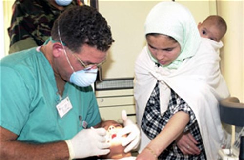 A Navy Commander performs a dental check-up on a young Moroccan girl as her mother and little sister look on. He is part of MEDFLAG 2003, a joint U.S. service medical training and humanitarian mission held every year in Africa. This year&#39;s MEDFLAG is being held in Er Rachidia, Morocco and surrounding villages.
(Photo submitted by NAVEUR Public Affairs)