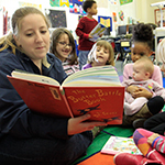 Woman reading to young children.