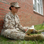 Service member sitting outside reading