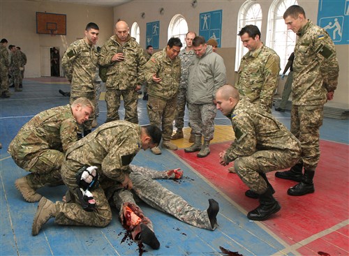 U.S. Special Operations Command Europe Commander Maj. Gen. Gregory J. Lengyel and ssoldiers from the Ukrainian Ministry of Defense look on as a Ukrainian soldier provides point of injury combat casualty care to a simulated casualty during an exercise Dec. 4 in Kirovohrad, Ukraine. SOCEUR deployed a medical team to Western Ukraine in November to coach and mentor Ukrainian Ministry of Defense personnel on basic battlefield medical procedures, coaching and mentoring more than 300 Soldiers during six three-day classes over the course of 30 days.