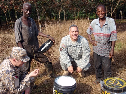 Michigan National Guardsman Master Sgt. Santos Feliciano and Latvian National Armed Force 1st Sgt. Marteen Kupcs pose with workers from a rubber plantation in Liberia, Jan. 16, 2013. Michigan and Latvia are partners in the Department of State and DoD State Partnership Program and Liberia is Michigan's newest partner. The soldiers were there to assist with noncommissioned military officer development and other core military discipline and civil defense initiatives. While driving from one site to another, the soldiers spotted the workers and pulled their vehicle over to talk to them. Establishing relationships with the local community is a key factor in assisting partner countries, especially a country such as Liberia that is recovering from years of civil war. 