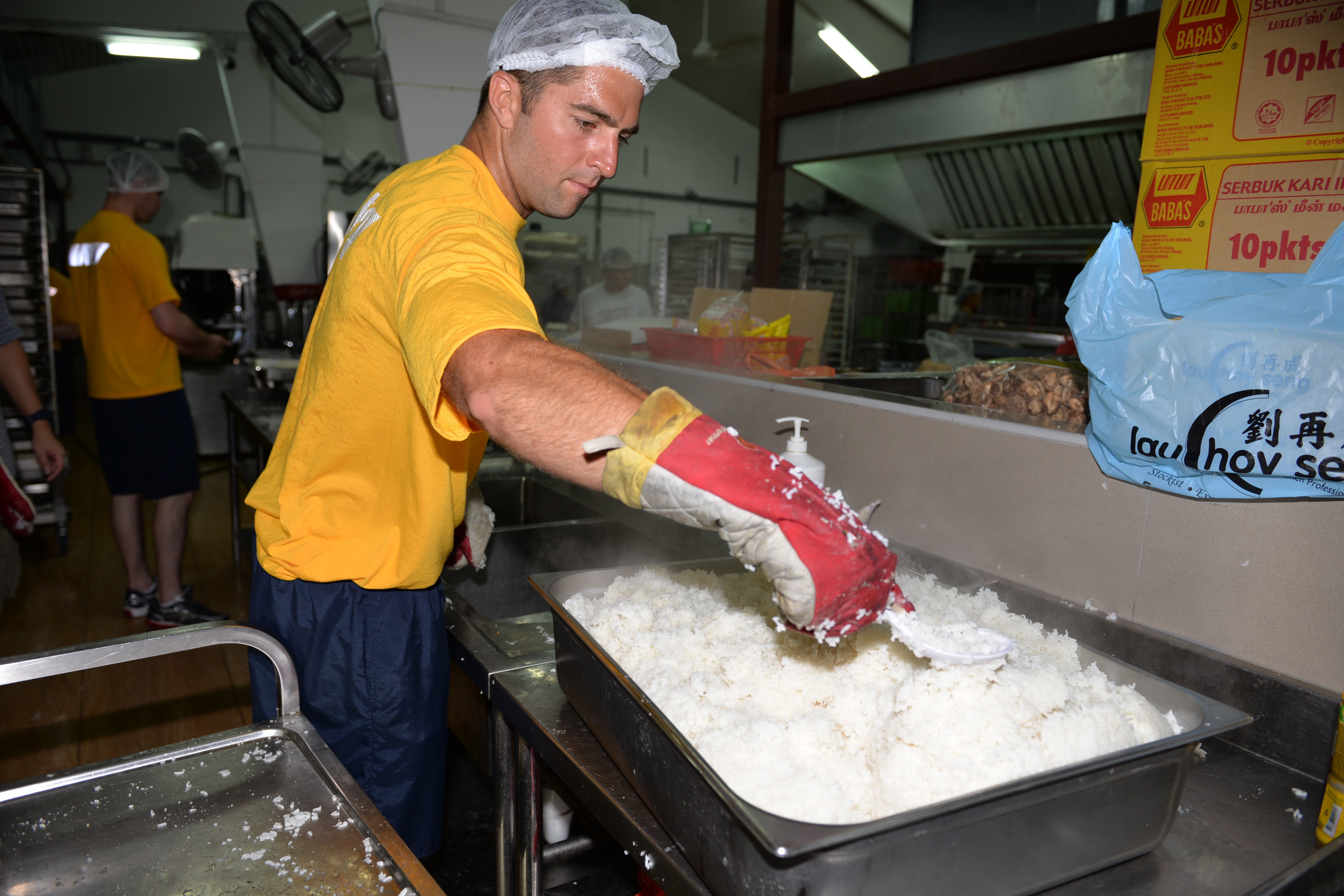 SINGAPORE (May 21, 2016) - U.S. Navy LT. Mike Burbelo, assistant marine transportation specialist, Military Sealift Command Far East (MSCFE), prepares and cooks a tray of white rice during a volunteer event at Singapore's Willing Hearts charity organization and soup kitchen May 21, 2016. Burbelo, a Daytona, Fla. native, along with four other Sailors participated in a community relations event as part of a theater-specific training course with MSCFE. (Official U.S. Navy photo by Marc Ayalin)