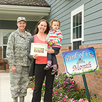 Service member with his family in front of his home