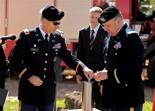 Col. Shawn Fritz, representing U.S. European Command, adds a U.S. EUCOM coin to a ceremonial time capsule to be placed in the foundation of the new three-bay garage with the help of Lt. Col. Peter Wisti from the U.S. Embassy Riga's Office of Defense  ooperation, during a ground-breaking ceremony at the firehouse in Gulbene, Latvia May 14, 2012. 