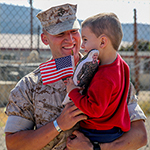 Service member with child holding flag