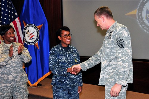 U.S. European Command Deputy Commander Lt. Gen. William Garrett III presents a coin to PO1 Prescilla Dorsey, Career Counselor for outstanding duty performance.