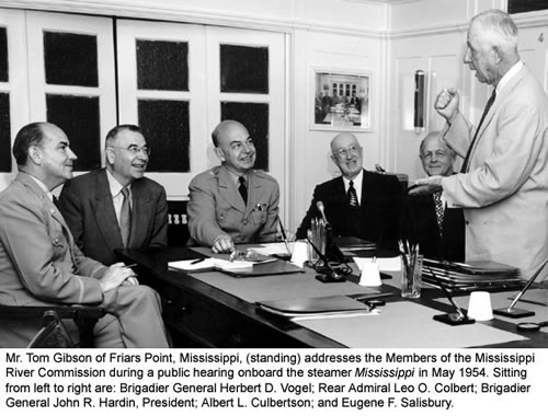 Mr. Tom Gibson of Friars Point, Miss., (standing) addresses the Members of the Mississippi River Commission during a public hearing aboard the steamer Mississippi in May 1954.  Sitting from left to right are:  Brigadier General Herbert D. Vogel; Rear Admiral Leo O. Colbert; Brigadier General John R. Hardin, President; Albert L. Culbertson; and Eugene F. Salisbury.