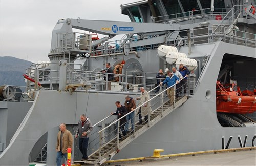 Delegates disembark from the Norwegian Coast Guard ship Harstad, after a brief underway during the Arctic Security Forces Roundtable (ASFR) 2014. More than 50 representatives from 11 nations participated in the annual event that is designed to increase collaboration and cooperation in regards to security and safety challenges in the Arctic.