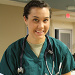 A female doctor standing at a desk with a binder of paperwork