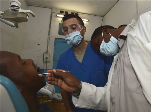 U.S. Army Capt. Michael Silva, 404th Civil Affairs Battalion dentist, center, and Dr. Hassan Ahmed, Ali Sabieh dentist, examine a patient at the Ali Sabieh Medical Clinic in Djibouti, Africa, Sept. 12, 2015. The 404th CA BN team, assigned to Combined Joint Task Force-Horn of Africa, offers guidance and shares knowledge with Djiboutian medical personnel during a Medical Civic Action Program event. (U.S. Air Force photo by Senior Airman Nesha Humes) 