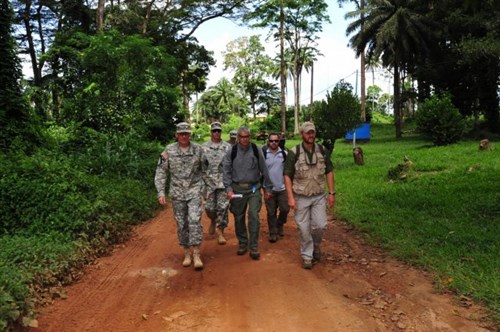 Maj. Gen. Gary Volesky, commander of the Joint Forces Command - United Assistance and 101st Airborne Division (Air Assault); Lt. Col. Lee Hicks, JFC-UA command engineer; Capt. Tad Reed, aide to the JFC-UA commander; Gregg Gross, engineering contractor; Sam Sells, military liaison officer, U.S. Agency for International Development; Armed Forces of Liberia Capt. A. J. Halley Moore, 1st Battalion commander; and Scott Dehnisch, military liaison officer, USAID, walk down a street Nov. 3, 2014, in Ganta, Liberia, on their way to meet with local city and medical officials.