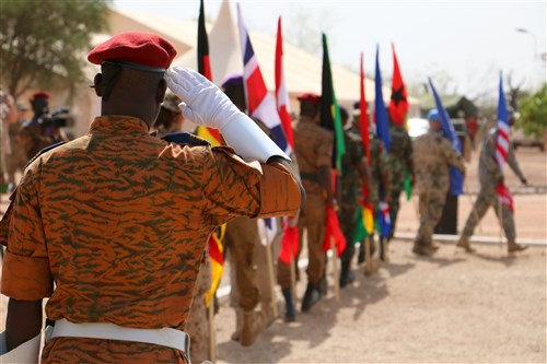 An officer from the Burkina Faso army salutes as international flags march past him during the Western Accord 16 Opening Day Ceremony May 2, 2016 at Camp Zagre, Ouagadougou, Burkina Faso. Western Accord 16 is an annual combined, joint exercise designed to increase the ability of African partner forces and the U.S. to exercise participants’ capability and capacity to conduct African Union/United Nation mandated Peace Operations. (U.S. Army photo by Staff Sgt. Candace Mundt/Released)