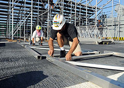 Contractors assemble bleachers on the flight deck of the multipurpose amphibious assault ship USS Bataan (LHD 5) in preparation for the Navy-Marine Corps Classic basketball game between the University of Florida Gators and the Georgetown University Hoyas. (U.S. Navy photo by Mass Communication Specialist 3rd Class Dylan Miles/Released) 