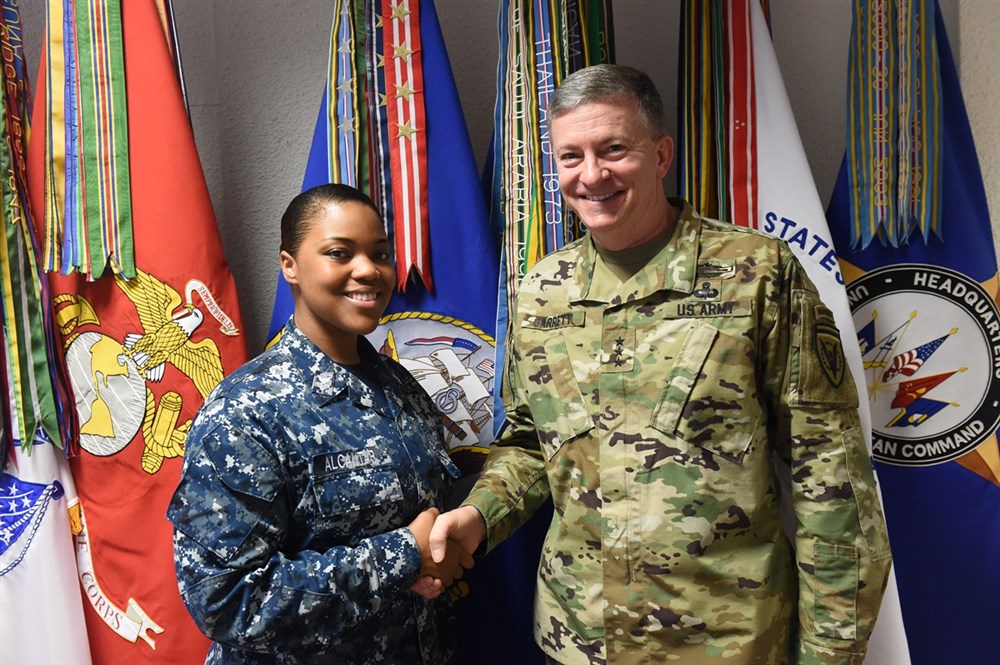 U.S. European Command Deputy Commander Lt. Gen. W. Burke Garrett III presents a coin to GM1 Jessica Alcantar, Armory NCOIC, for outstanding duty performance Apr. 15, 2016.