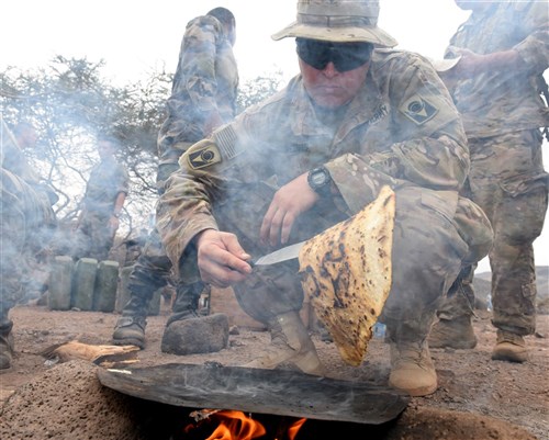 U.S. Army Spc. Christopher Reeves, 2-124 Infantry Battalion mechanic, grills flatbread during a French Desert Survival Course near Arta Beach, Djibouti, Jan. 13, 2016. Using techniques that can be used in survival situations, students worked together to make a meal for the whole group.