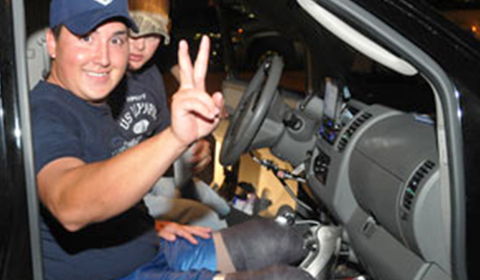 A wounded warrior in his car making the peace sign and smiling