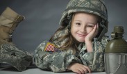 Lily, daughter of Army Sgt. James Newby, grins as she poses for portraits with her father's uniform items on Fort Meade, Md. U.S. Air Force photo by Staff Sgt. Vernon Young Jr.