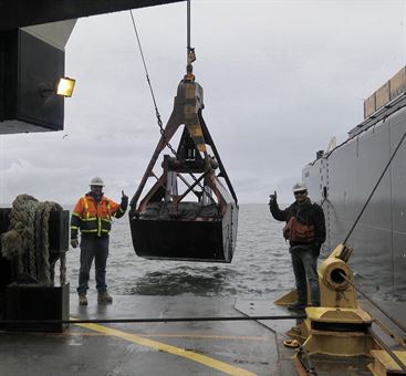 Maintenance and deepening dredging of the inner harbor at Grays Harbor has begun. The first bucket of dredged material pictured here, a 35-cubic-yard rehandling bucket, is flanked by American Construction&#39;s Aaron McMahill and Chris Raymond.