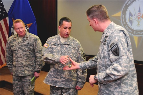 U.S. European Command Deputy Commander Lt. Gen. William Garrett III presents a coin to Staff Sergeant Amador Sanchez, current operations NCOIC, for outstanding performance.