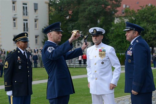 Command Chief Master Sgt. Craig Adams inspects a non-commissioned officer cutlass during a U.S. European Command Senior Enlisted Leader Change of Responsibility Ceremony at Patch Barracks Aug. 14 2013, while outgoing SEL Fleet Master Chief Roy Maddocks and U.S. EUCOM commander Gen. Philip Breedlove look on. The passing of the cutlass signified the passing of responsibilities to Chief Adams as U.S. EUCOM's new senior enlisted leader. General Breedlove officiated the ceremony, which included the retirement of Master Chief Maddocks after 36 years in service.