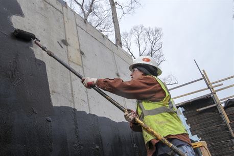 ARLINGTON, Va. – Jonathan Heuneman, a contractor working on the Arlington National Cemetery’s Millennium Expansion project, rolls sealant on the concrete wall of a bridge at the site, March 22, 2016. The new bridge, when complete, allows traffic to flow over a restored stream in the 27 acre expansion project. (U.S. Army photo/Patrick Bloodgood) 